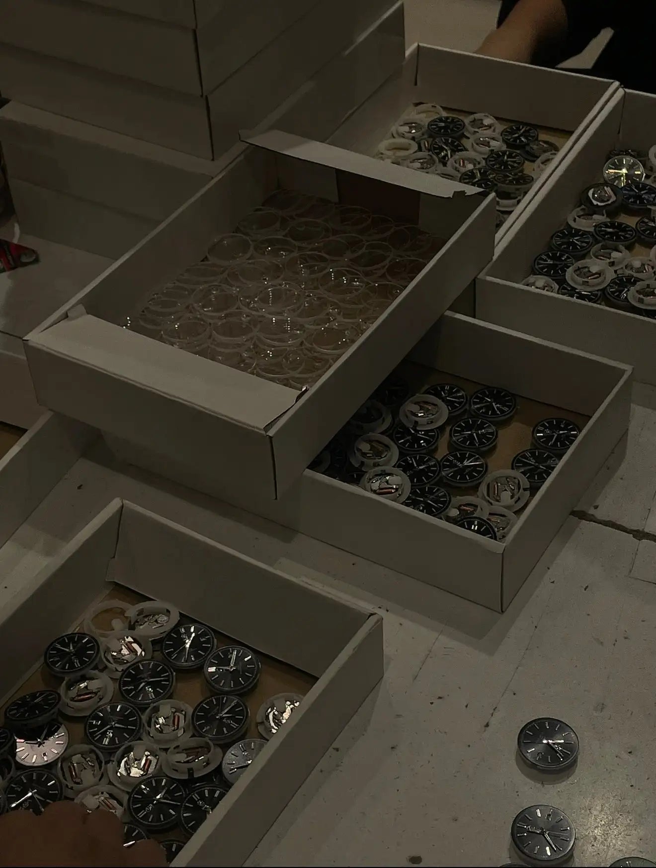 Cadrans de montres noirs et argentés dans des boîtes en carton.