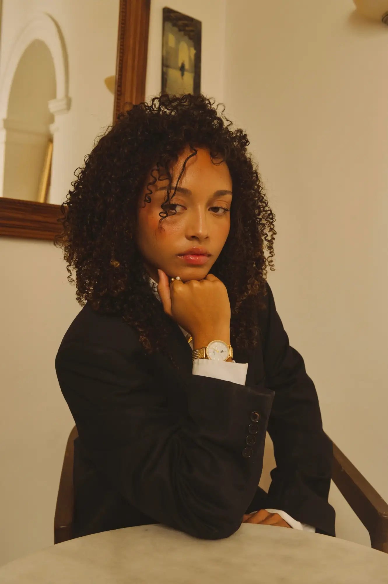 Montre à ton or avec cadran blanc et bracelet noir portée au poignet.